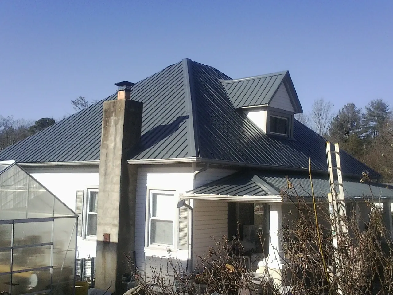 Dark blue standing seam metal roof on a white farmhouse with dormer — Slate & Tile Roof Repair by Roofing Brothers in Racine