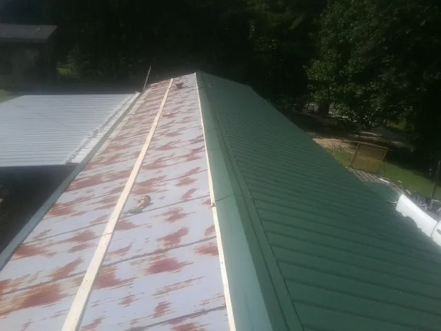Old rusted panels beside newly installed green metal roofing — Wind Damage Roof Repair by Roofing Brothers in Racine