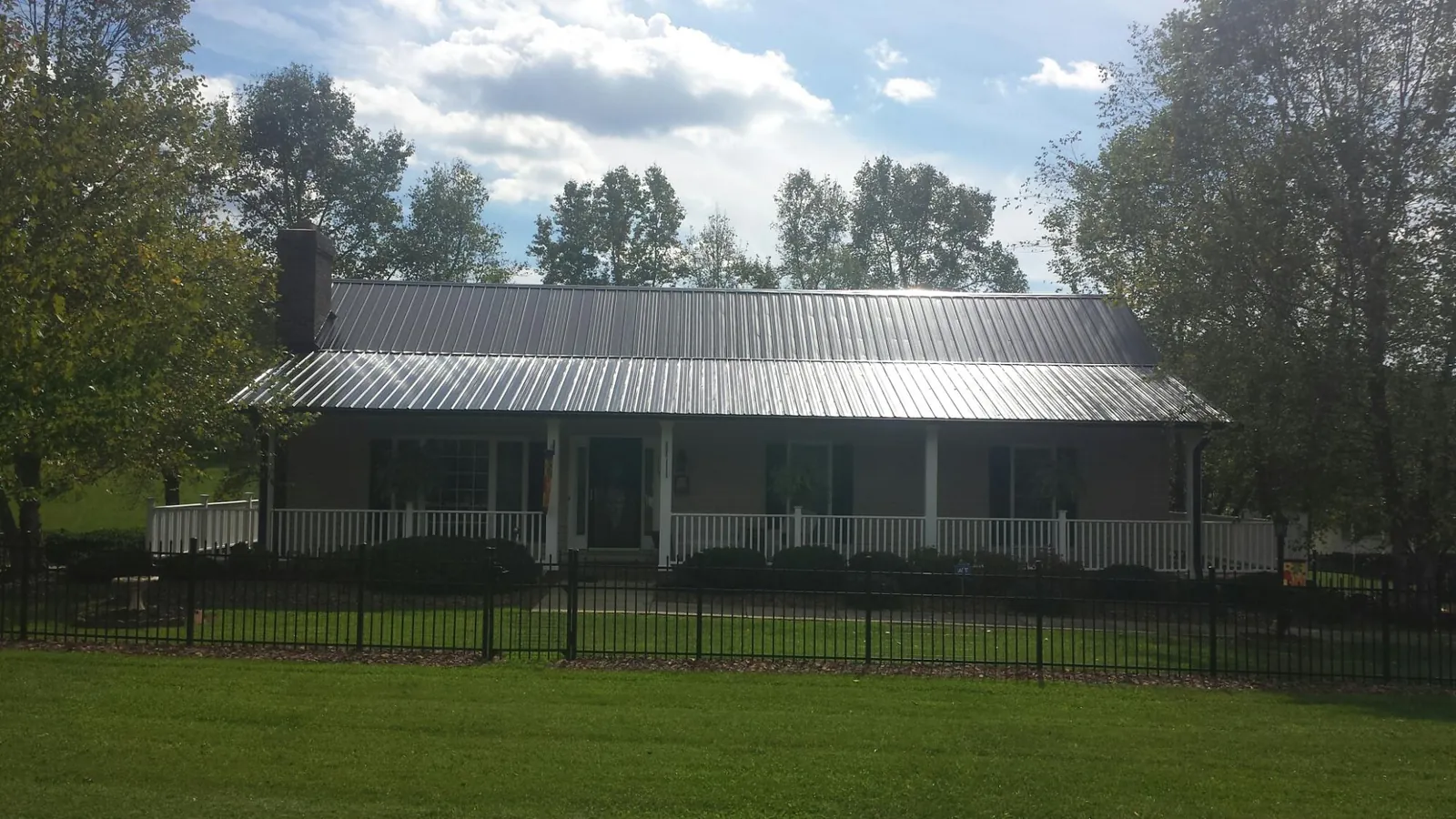Gray metal roof on a brick ranch with a full width front porch — Gutter Guard Installation work by our crew in Racine